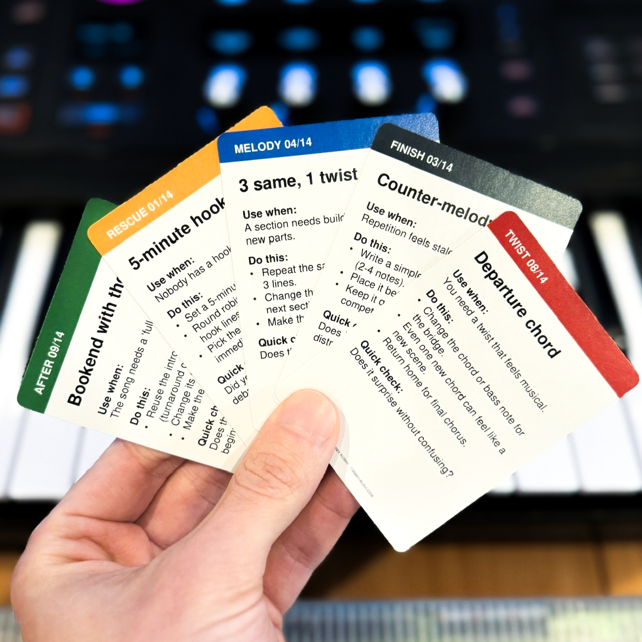 Session Cards held in front of studio equipment, showing cards from multiple categories